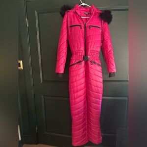 Bright pink belted ski jumpsuit with black faux fur hood